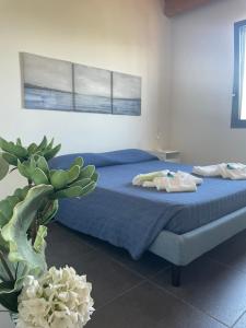 una camera da letto con un letto con lenzuola blu e una pianta di Villa Aloe a Menfi