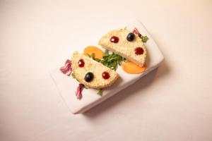 a white plate with a sandwich with two faces on it at Hotel Villa Pascucci in Durrës