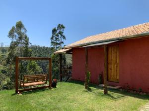 a red house with a bench in the yard at Chalés Água azul in Santo Antônio do Pinhal