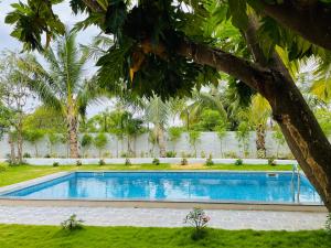 una piscina en un patio con árboles en Yasuragi Boutique Resort, en Shencottah