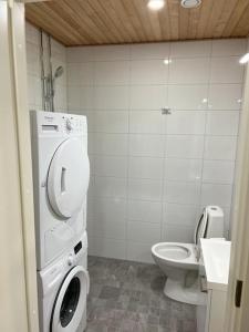 a bathroom with a toilet and a washing machine at Ihana huoneisto juna aseman vieressä. in Vantaa