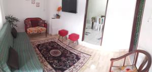 a living room with a rug and a chair and a mirror at Casa de Praia in Ilhabela