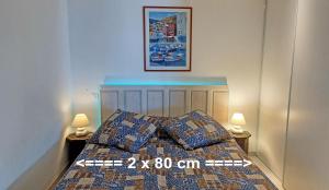 波爾蒂喬的住宿－Les Terrasses du Pano - 76 m2 au calme - Jardin - Barbecue - Transats - Pleine vue mer - Wifi Fibre，一间卧室配有一张带两盏灯的床,墙上挂着一张照片