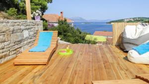 a wooden deck with a chair and a toy at Eco Sunshine Apartments Lumbarda in Lumbarda