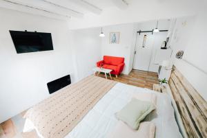 Habitación blanca con cama y silla roja en Hotel Boutique La Mexicana Suites & Beach, en Punta del Este