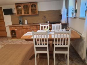a kitchen with a wooden table and two white chairs at Komfortowy apartament nad Zalewem Sulejowskim in Sulejów +32 photos