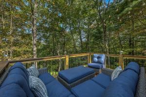 a patio with a couch and a chair on a deck at Golden Eagle GA Cabin - Hot Tub, Firepit & Fast WiFi in Blue Ridge