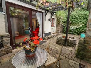 a patio with a table with a pot of flowers on it at Tinkletod in Clevedon