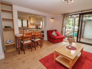 a living room with a table and a red chair at Tinkletod in Clevedon