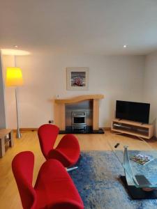 uma sala de estar com cadeiras vermelhas e uma televisão de ecrã plano em West End & EICC with Parking em Edinburgo