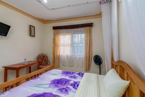 een slaapkamer met een bed met paarse lakens en een raam bij Airport Side Hotel Entebbe in Entebbe