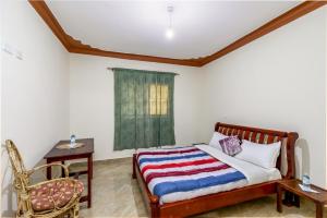 een slaapkamer met een bed, een stoel en een raam bij Airport Side Hotel Entebbe in Entebbe