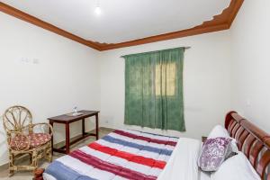 a bedroom with a bed and a table and a window at Airport Side Hotel Entebbe in Entebbe