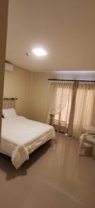1 dormitorio con cama blanca y ventana en Apart hotel Florida, en Ciudad del Este