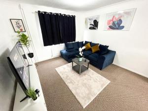 un soggiorno con divano blu e tavolo di 3 Bedroom House With Free Parking a Chatham