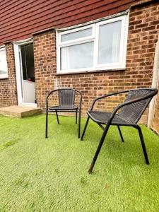 due sedie sedute sull'erba di fronte a un edificio di 3 Bedroom House With Free Parking a Chatham