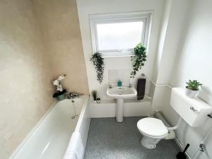 a bathroom with a toilet a sink and a bath tub at 3 Bedroom House With Free Parking in Chatham