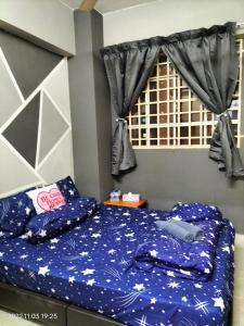 a bedroom with a bed with blue sheets and a window at Yuyu homestay in Johor Bahru