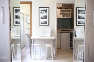 una cocina con mesas blancas y taburetes en una habitación en Unhotel - Charmoso Studio no Leblon, entre a Praia e Rua Dias Ferreira, en Río de Janeiro