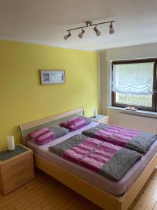 a bedroom with a bed with pink sheets and a window at Ferienwohnung Am Elzbach in Monreal