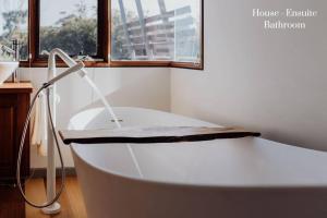 baño con bañera blanca y ventana en Miramar Beach House, en Seymour