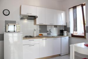 eine weiße Küche mit weißen Schränken und einem Tisch in der Unterkunft Lily's lovely apartments in Fažana