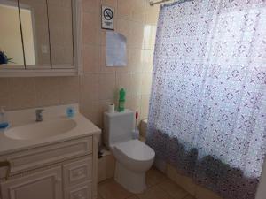 a bathroom with a toilet and a sink and a shower curtain at Hostal Rosario in La Serena
