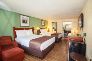 una habitación de hotel con 2 camas y una silla en Travelodge by Wyndham Macon West, en Macon