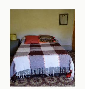 uma cama com um cobertor listrado em cima em Aguaribay cabañas em San Javier