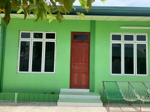 a green house with a red door and windows at Arrow in Vashafaru