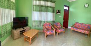 a living room with two chairs and a flat screen tv at Arrow in Vashafaru