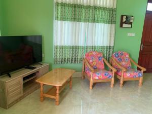 a living room with two chairs and a television at Arrow in Vashafaru