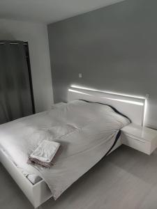 a white bed in a white room with a mirror at magnifique villa avec piscine et spa in Merville