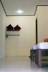 ボロブドゥールにあるPenginapan Homestay Mudiyono Syari'ahの赤い枕が備わる壁にベッドが付く部屋