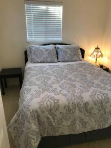 ein Schlafzimmer mit einem Bett mit einer Decke und einem Fenster in der Unterkunft Cozy Cottage House B with Double Carport in Twin Falls