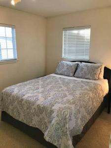 a bedroom with a bed with a blanket and two windows at Cozy Cottage House B with Double Carport in Twin Falls