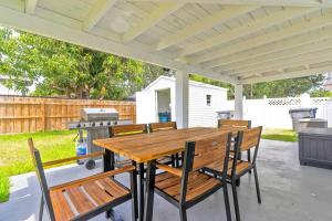 een houten tafel en stoelen op een patio met een grill bij Modern Getaway 4BRs House with Pool and Game Room in Hollywood