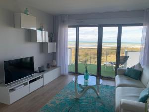 a living room with a couch and a tv and a table at Face mer pieds dans l'eau in Berck-sur-Mer