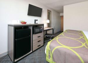 a hotel room with a bed and a desk with a tv at Super 8 by Wyndham Amarillo in Amarillo