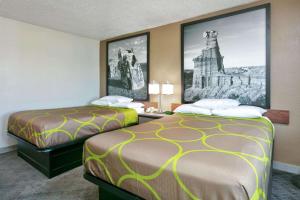 two beds in a hotel room with pictures on the wall at Super 8 by Wyndham Amarillo in Amarillo