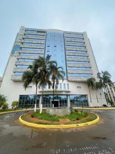 a large building with palm trees in front of it at Flat em Taguatinga in Taguatinga