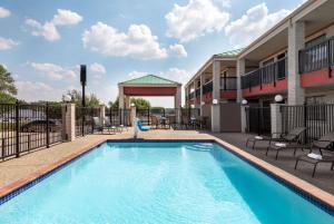 uma piscina em frente a um edifício com cadeiras em Days Inn by Wyndham San Antonio Near Fiesta Park em San Antonio