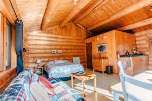 Dormitorio en cabaña de madera con cama y sofá en Rocky Mountain Escape Log Cabin Rentals - Rock Lake en Rock Lake Lodge Provincial Park