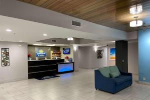 Sala de espera con silla azul y TV en Days Inn & Suites by Wyndham Ridgeland, en Ridgeland