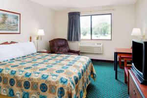 um quarto de hotel com uma cama e uma cadeira e uma janela em Super 8 by Wyndham Omaha Eppley Airport/Carter Lake em Omaha