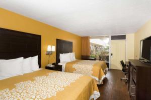 a hotel room with two beds and a flat screen tv at Days Inn & Suites by Wyndham Port Richey in Port Richey