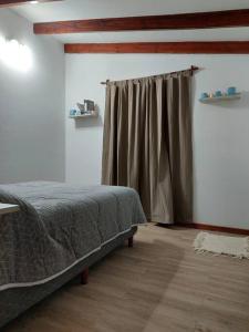 1 dormitorio con cama y cortina en Lourdes host en Ushuaia