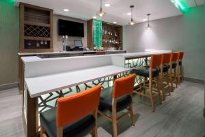 a bar with orange chairs and a white counter at La Quinta by Wyndham LAX in Los Angeles