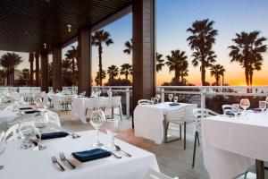 a restaurant with white tables and chairs and palm trees at Wyndham Grand Clearwater Beach in Clearwater Beach