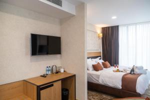Hotel Solum Roof Top في تبليسي: غرفة فندقية بسرير وتلفزيون بشاشة مسطحة